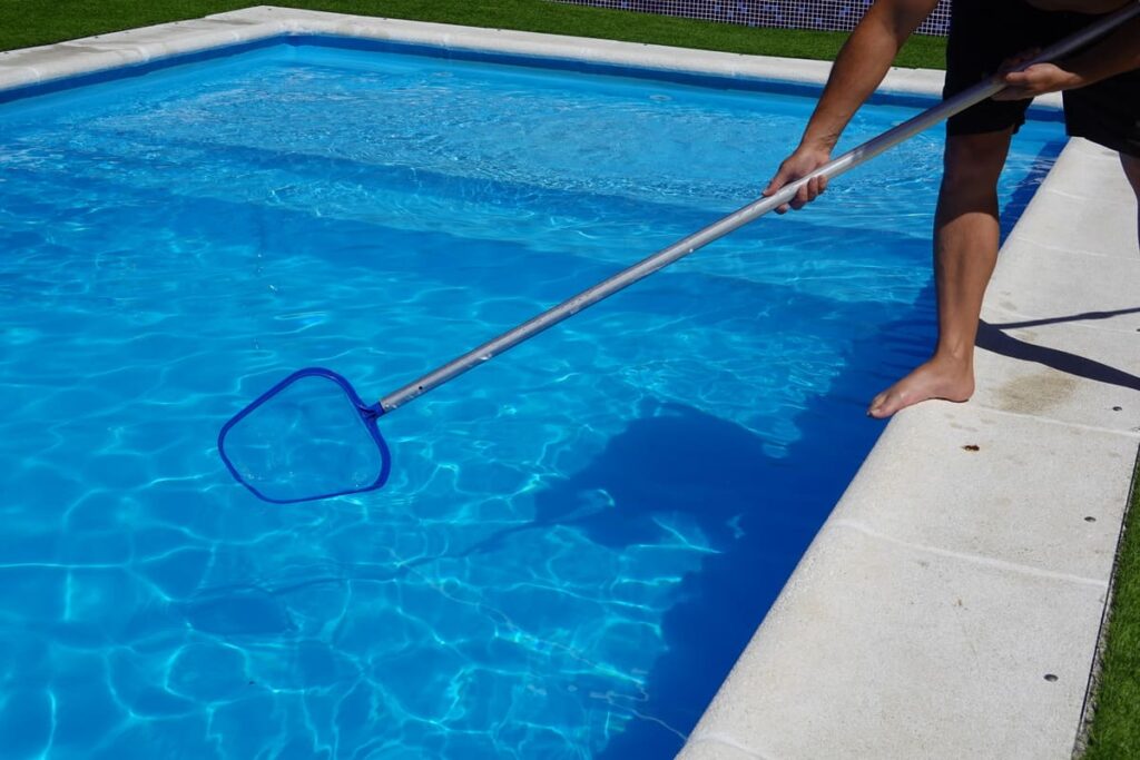 Homem limpando piscina com peneira