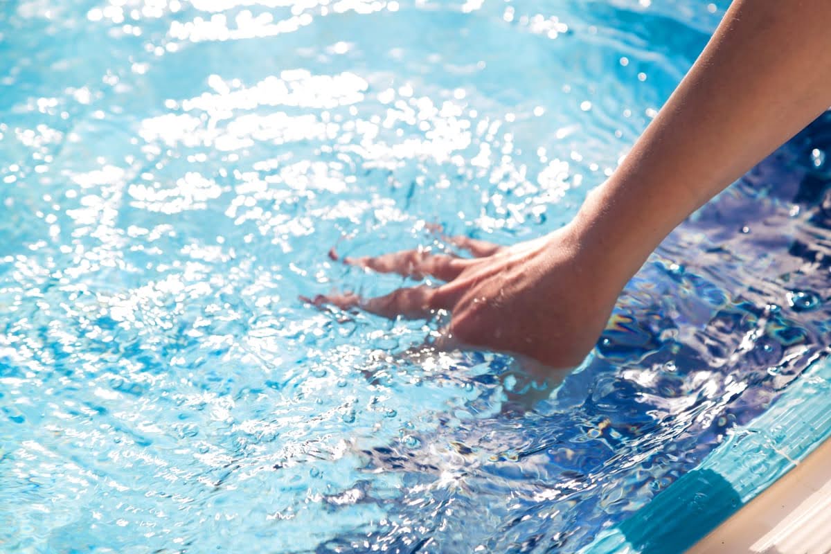 Mão de mulher dentro de água da piscina em movimento