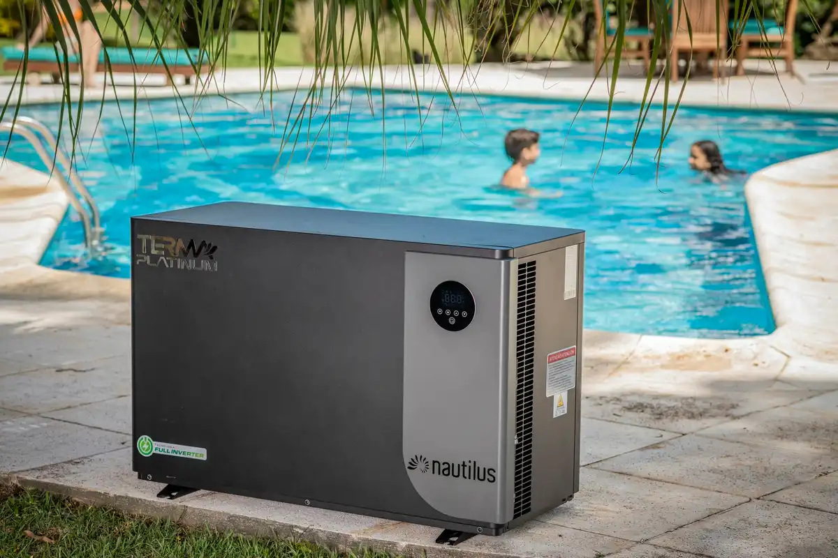 Bomba de calor Nautilus ao lado de uma piscina ao ar livre com duas pessoas nadando.